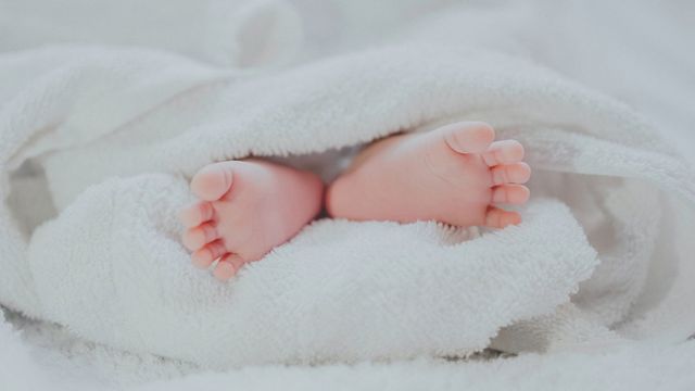 A baby's feet poke out the bottom of a towel. 