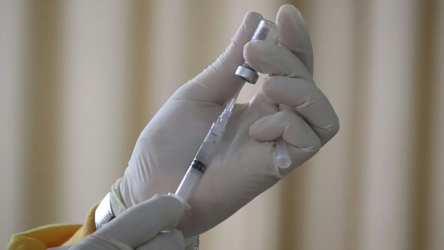 A person drawing up a vaccine into a syringe. 